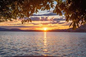 ein Sonnenuntergang beim das See das Oberer, höher Kante ist bedeckt durch Blätter foto