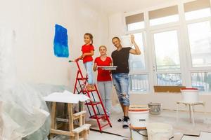 Zuhause Verjüngungskur, Dekoration und Gemälde glücklich Familie lächelnd und posieren, das Mädchen ist halten ein Farbe Walze foto