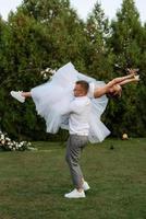 das zuerst tanzen von das Bräutigam und Braut im ein kurz Hochzeit Kleid auf ein Grün Wiese foto