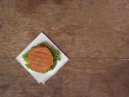 oben Aussicht von Appetit Burger gegen ein hölzern Tisch. Kopieren Raum foto