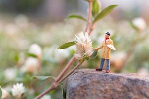 Miniaturkünstler, der einen Pinsel hält und Blumen im Garten malt foto