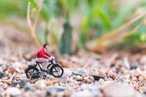 Miniaturreisender, der Fahrrad fährt und das Weltkonzept erkundet