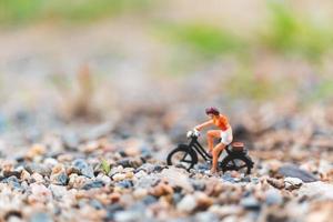 Miniaturreisender, der Fahrrad fährt und das Weltkonzept erkundet