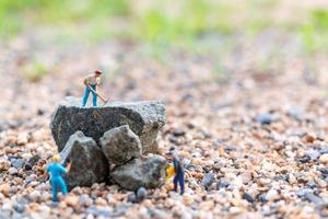 Miniaturarbeiter auf einem Felsen, Teamwork-Konzept foto