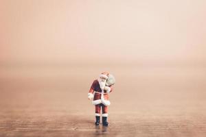 Miniatur-Weihnachtsmann, der eine Tasche trägt, Weihnachtsfeierkonzept foto