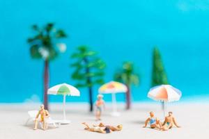 Miniaturmenschen, die Badeanzüge tragen, die auf einem Strand entspannen, Sommerkonzept