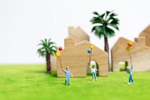Miniaturfamilie, die in einem Feld mit Luftballons geht, glückliches Familienzeitkonzept foto