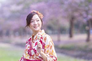 japanisch Frau im traditionell Kimono Kleid halten Süss Hanami Dango Dessert während Gehen im das Park beim Kirsche blühen Baum während Frühling Sakura Festival mit Kopieren Raum foto