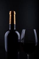 Nahaufnahme Weinflasche und Glas mit schwarzem Hintergrund foto
