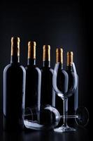 Weinflaschen und Glas mit schwarzem Hintergrund foto