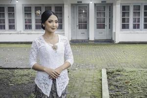 ein jung indonesisch Frau mit ein glücklich erfolgreich Ausdruck tragen ein Weiß kebaya. Kartini Tag Konzept. foto