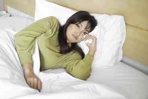 ein traurig jung asiatisch Frau ist Weinen während Lügen auf das Bett foto