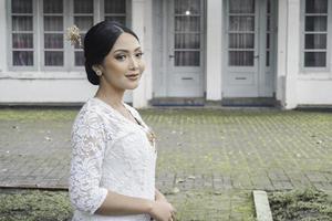 ein jung indonesisch Frau mit ein glücklich erfolgreich Ausdruck tragen ein Weiß kebaya. Kartini Tag Konzept. foto