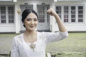 ein jung indonesisch Frau mit ein glücklich erfolgreich Ausdruck tragen ein Weiß kebaya. Kartini Tag Konzept. foto