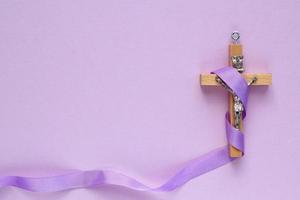 Christian religiös hölzern Kreuz Kruzifix mit violett Band auf lila Hintergrund. katholisch Religion Symbol. gut Freitag, Fastenzeit Jahreszeit, Palme Sonntag, Asche Mittwoch und heilig Woche Konzept foto