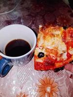 Scheibe von Pizza und ein beruhigend Tasse von Kaffee foto