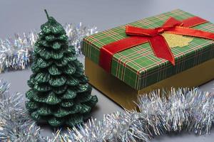 ein Box mit ein Geschenk zum Weihnachten und Neu Jahr, ein Grün Geschenk Box mit ein rot Band Bogen auf ein grau Hintergrund foto