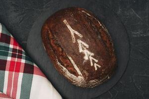 frisch gebacken warm köstlich Roggen runden Brot und ein kariert Küche Handtuch Nahansicht. das Konzept von gesund Essen foto