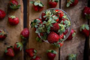 Erdbeeren in einem Glas und auf einem Tisch foto