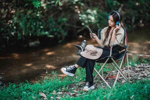 junge asiatische frau, die auf stuhl sitzt und musik vom kopfhörer hört foto