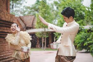 junges paar spritzt wasser aus der schüssel auf dem songkran festival foto