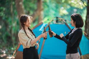 junge frauen jubeln und trinken getränke vor dem campingzelt foto