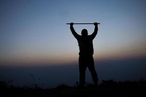 Silhouette von Jubel Wandern Mann öffnen Waffen zu das Sonnenaufgang Stand auf Berg foto