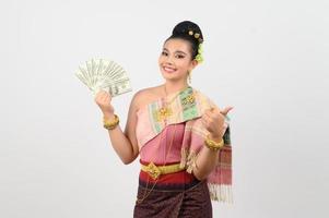 Porträt von schön thailändisch Frau im traditionell Kleidung posieren mit Ventilator Banknote foto