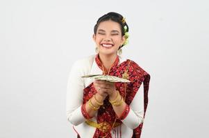 Porträt von schön thailändisch Frau im traditionell Kleidung posieren mit Ventilator Banknote foto