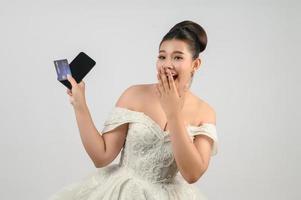 jung asiatisch schön Braut Buchung mit Anerkennung Karte und Smartphone im Hand foto