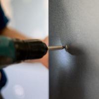 das Prozess von Schrauben das schrauben, Installation von ein gleiten Tür Kleiderschrank. foto