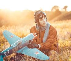 Kerl im Jahrgang Kleider Pilot mit ein Flugzeug Modell- draußen foto