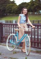 junge schöne, elegant gekleidete Frau mit Fahrrad foto