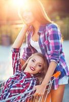 zwei glücklich schön Teen Mädchen Fahren Einkaufen Wagen draußen foto
