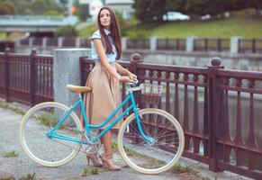 junge schöne, elegant gekleidete Frau mit Fahrrad foto