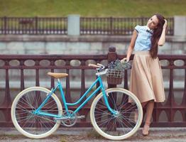 junge schöne, elegant gekleidete Frau mit Fahrrad foto