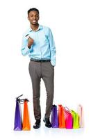 glücklich afrikanisch amerikanisch Mann mit Einkaufen Taschen und halten Anerkennung Karte auf Weiß Hintergrund foto