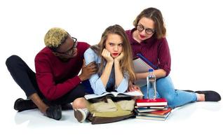 drei glücklich Studenten Sitzung mit Bücher, Laptop und Taschen foto