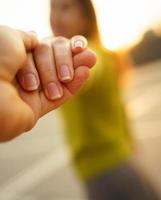 glücklich jung Frau ziehen Leute Hand - - Hand im Hand Gehen auf ein hell sonnig Tag foto