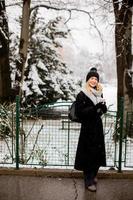 jung Frau mit warm Kleider im kalt Winter Schnee Trinken Kaffee zu gehen foto