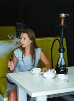 schön Frau Rauchen ein Huka und Trinken Tee im ein Cafe foto