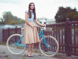 junge schöne, elegant gekleidete Frau mit Fahrrad foto