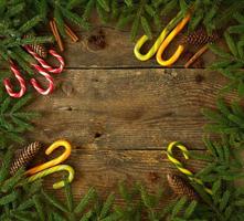 Weihnachten Baum Ast mit Zapfen, Zimt, Diptam und Süßigkeiten Stock auf hölzern Hintergrund mit Copyspace foto