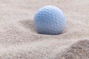 Golfball im Sand mit Kopierraum foto