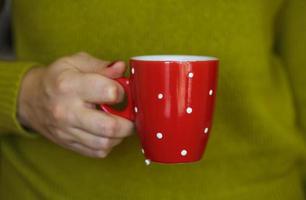 Frau Hände halten ein gemütlich rot Becher foto