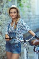 glücklich Frau mit Fahrrad auf Straße von alt Stadt, Dorf foto