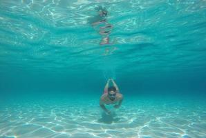 jung Bart Mann mit Brille Tauchen im ein Blau sauber Wasser foto