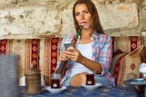 Frau Rauchen ein Huka und Verwendet Smartphone im ein Cafe im Istanbul, Truthahn foto