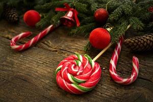 Weihnachtsgrenze mit Tannenzweigen, Zapfen, Weihnachtsschmuck und Zuckerstange auf rustikalen Holzbrettern foto