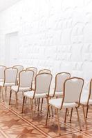Reihe von festlich elegant Gold Metall Stühle mit Weiß Stoff drinnen Halle. foto